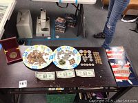 Full overview of the coin collection on paper plates including $2 bills and coin albums on the table