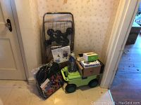 3 Wheel stair climbing folding cart with wheels folded against wall with AeroGarden box and several other boxes on top of a green cart.