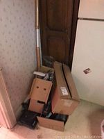 Boxes containing mop handles, vacuum parts, and other accessories in corner of room