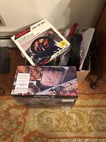 Three boxed kitchen appliances: Grill King Cook Top Grill in white box, Flavor Chef Cooker box showing a roast chicken, and a box under these two items.