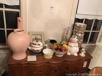 Overview photo of all items on the wooden chest including the large pink vases, bowl with glass fruit, bunny cookie jar, candle holders, covered bowls and plate.