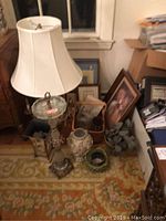 Lamp with crystals and fabric shade next to various decorative items on the floor including framed picture