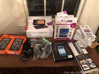 Multiple electronic items on table including Jazz 8" tablet, Prestigio 7" tablet, Amazon Fire tablets, charger cables, and other accessories.