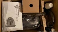 Bissell SpotClean user guide and spot cleaner unit inside box with protective packaging.