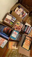 Top-down view of boxes containing multiple books mostly on cooking and wellness, showing a variety of titles and formats.