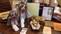 Photo of assorted religious statues, framed prayers, and small decorative items on a table.