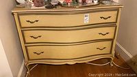 Full view of vintage blonde dresser with three drawers and brass handles showing its overall shape, color, and condition.