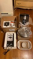 Full overview of the lot items including multi cooker, hot pot system, green pan induction cooker and blender parts in packaging