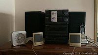 Wide view showing the Panasonic stereo system with two Sun speakers, the Timex clock radio, and the Uniden cordless phone on a wooden surface.