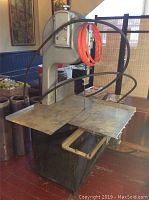 Full view of large heavy-duty butcher's bandsaw meat cutter with sliding table and blade guides.