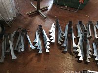 Photo of multiple stacked metal joist hangers on a floor showing their size and design.