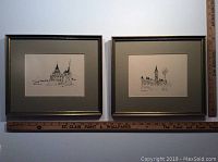 Two framed architectural ink sketches side by side on a wall with a measuring stick below showing about 11 by 13 inch frames.
