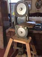 Full view of the older Craftmaster bandsaw on a hardwood wooden base showing the metal frame and blade area.