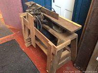 Side angle view of large 42-inch wood planer showing cast iron construction, wooden base, and motorized belts.