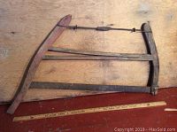 Photo of two antique bow saws laid flat showing wooden frames and metal blades with ruler for scale.