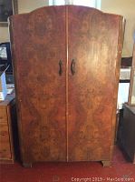 Front view of large wooden wardrobe showing symmetrical wood veneer pattern and black handles