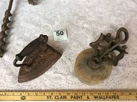 Top view of sad iron and wooden pulley on white lace cloth with measuring ruler.