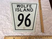 Front view of aluminum Wolfe Island Road 96 sign with ruler for scale showing approximate dimensions and visible aging.