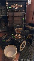 Black decorative items painted with strawberry floral motif including wooden washing board, sled, scale, kettle, candle holder, and watering pails