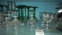 Clear crystal glassware collection with varied styles and sizes including green-stemmed glasses and cut crystal goblets.