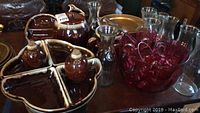 Photo of brown glazed stoneware divided trays with berry-shaped salt and pepper shakers along with glassware including a cranberry punch bowl and cups on a table.