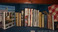 Assorted books including cookbooks and cooking magazines arranged on a shelf.
