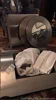 Photo showing the fireplace main structure with brushed stainless steel finish and attached circular mirror.