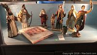 Photo of all six Santa Series collectible figures displayed on a surface alongside the hardcover book.