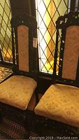 Pair of matching upholstered dining chairs with dark carved wooden frames and light floral upholstery on seat and back.