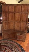 Front view showing curved wood bench with paneled cabinet doors above and below curved bench.
