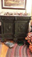 Front view of large dark stained wooden cabinet with two carved doors and decorative carvings along the top and bottom edges.