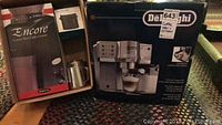 Boxed DeLonghi espresso machine and boxed Baratza grinder on patterned rug