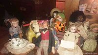 Wide shot of collection including dolls in various costumes and porcelain doll, toys, furniture and tea set arrayed together