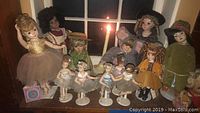 Full lot view showing multiple dolls, including ballerinas on stands, dolls in various outfits, displayed on a shelf.