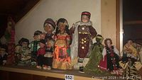 Wide view of 10 dolls displayed on a shelf representing diverse traditional costumes from various countries.