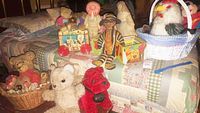 Wide shot of assorted stuffed animals including dolls, teddy bears, red dog, nesting boxes, and two baskets.