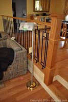 Metal floor lamp near staircase railing with curved patterned couch beside it.