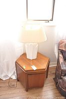 Full view of hexagonal wood table with ceramic lamp by window