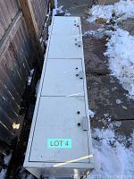Top view of the vintage white metal storage locker outdoors showing multiple hinged compartment doors with latch holes but no locks.