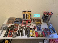 Wide shot of table displaying all packaged tools and accessories in original packaging, showing brands and item variety