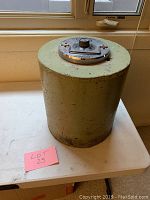 Front view of large vintage metal bank with combination dial on lid placed on a white table by window.