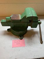 Full view of the green Columbian 3060 vice with rusted jaws and mounting base, on a white surface.