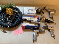 Photo showing the collection of air tools including air hoses, various pneumatic wrenches, and boxed grinder kit.