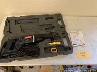 Ryobi RJ160V reciprocating saw inside molded plastic carrying case, cord wrapped, resting in open case on table.