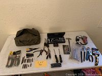 Full lot overview including tool bag, hand tools, hardware accessories displayed on white table.