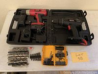 Two Craftsman cordless drills in black plastic cases with drill bits and accessories laid out on a flat surface