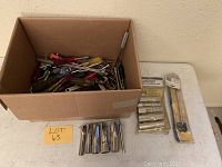 Box filled with various hand screwdrivers and chrome socket wrench attachments arranged on a table