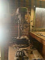 Full front view of Orbit drill press on bench with worktable and vise attached