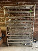 Frontal direct view of metal wire shelving unit with 8 shelves in storage environment with brick wall background, showing full structure and shelf arrangement.