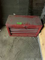 Red metal tool chest closed, dusty with visible wear
